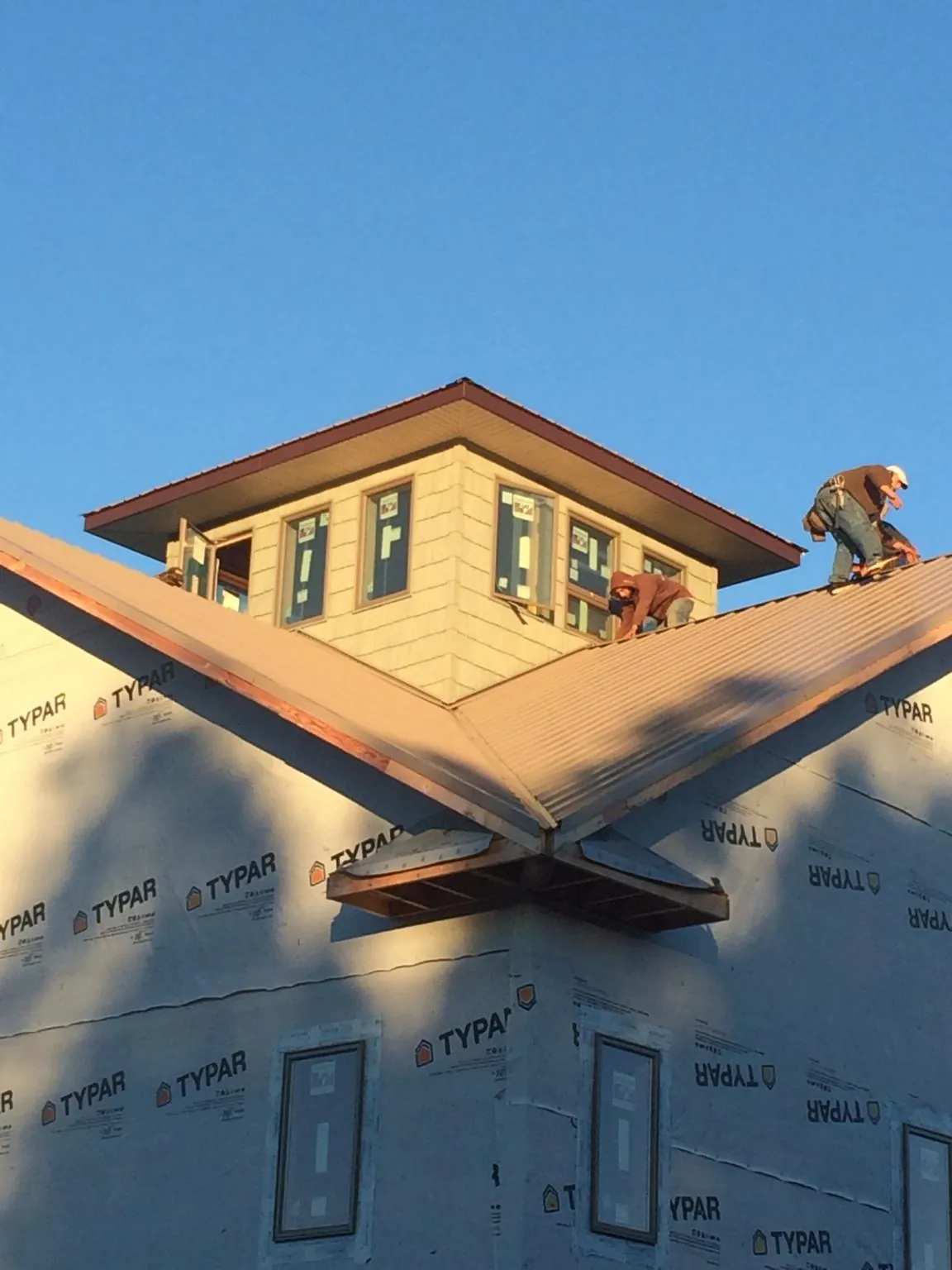 Roofers working around a rooftop cupola on a new metal roof at sunset — Roof Waterproofing in Creston by Roofing Brothers